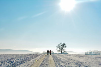 Rear view of people on snowy field against sky