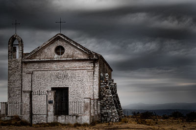 Old abandoned building on field against sky