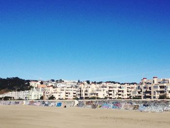 Houses on beach against clear blue sky