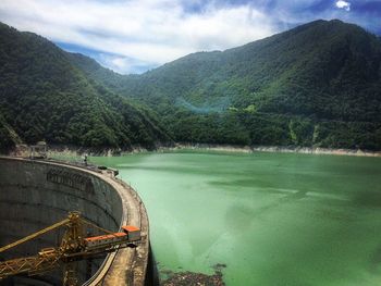 Green mountains by enguri dam against sky