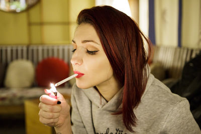 Close-up of woman igniting cigarette at home