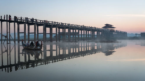 Bridge over lake against sky at sunset