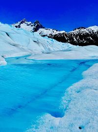 Scenic view of snowcapped mountains against blue sky