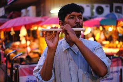 Close-up of man playing flute while standing in market