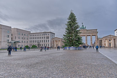 People on historic building in city against sky