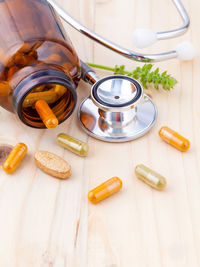 High angle view of medicines with herbs and stethoscope on wooden table