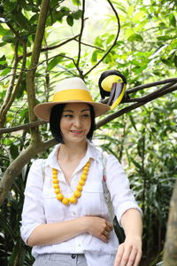 Portrait of smiling young woman standing against plants