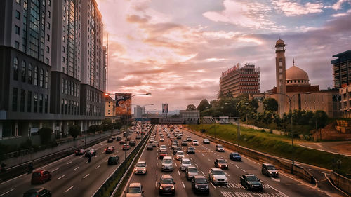 Traffic on road amidst buildings in city against sky