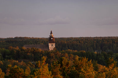 Tower amidst trees and buildings against sky