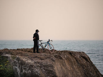 Rear view of man standing on beach against sky