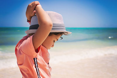 Little boy with curly hair looking down at a beach in the caribbean.