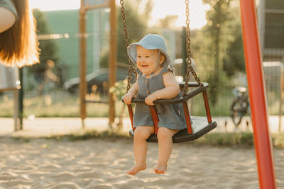 Portrait of young woman swinging at playground