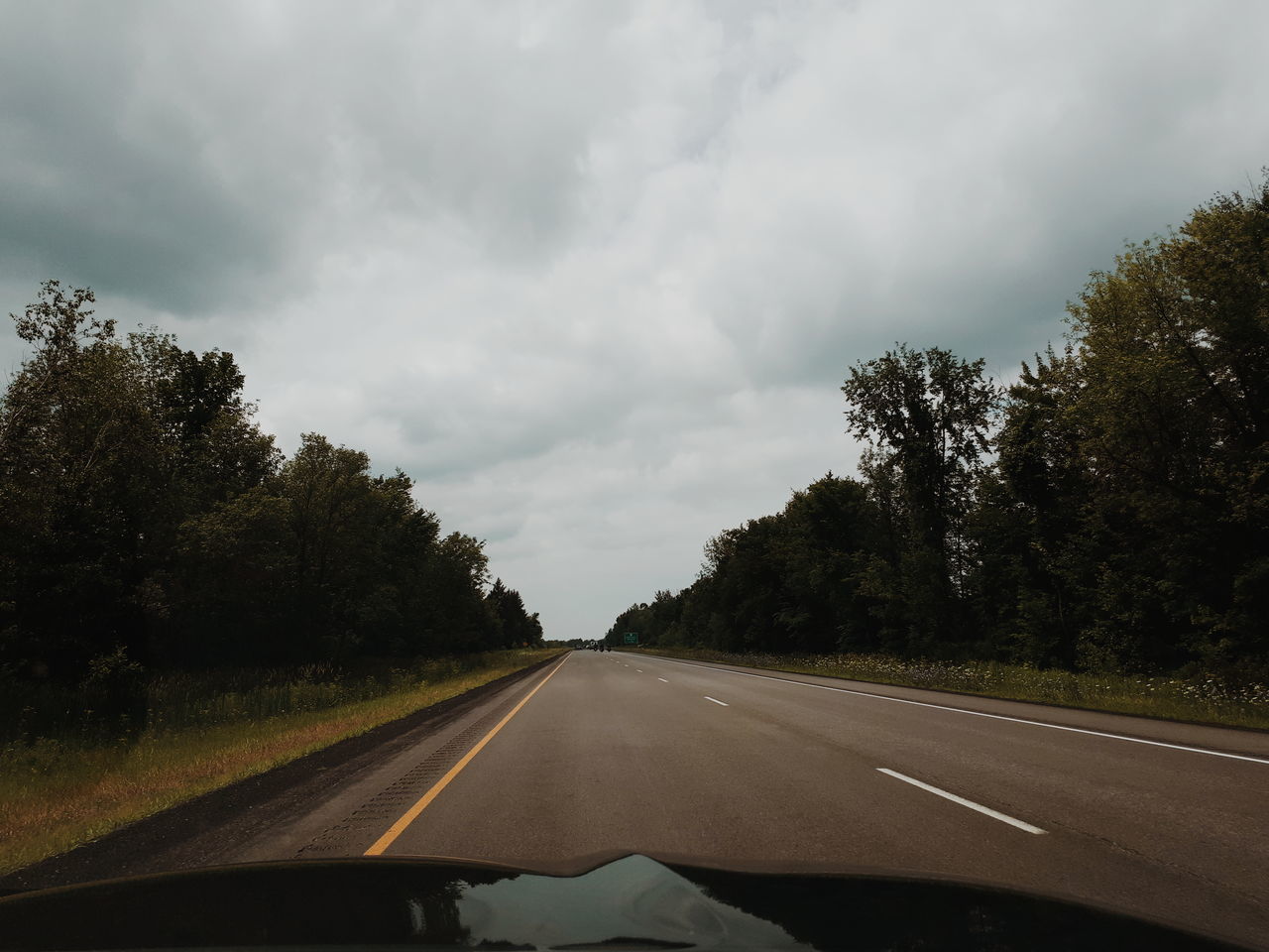 tree, transportation, cloud - sky, road, car, sky, windshield, plant, motor vehicle, land vehicle, vehicle interior, the way forward, transparent, direction, glass - material, mode of transportation, car interior, diminishing perspective, sign, no people, car point of view, road trip, outdoors, dividing line