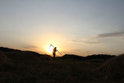 Silhouette man standing on land against sky during sunset