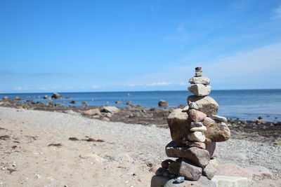 Stack of pebbles on beach against sky