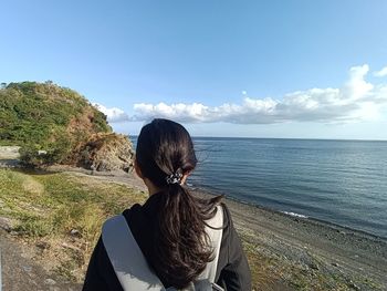 Rear view of woman looking at sea against sky