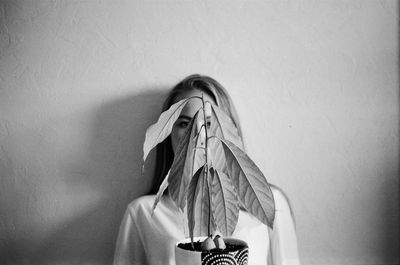 Portrait of woman covering face against wall