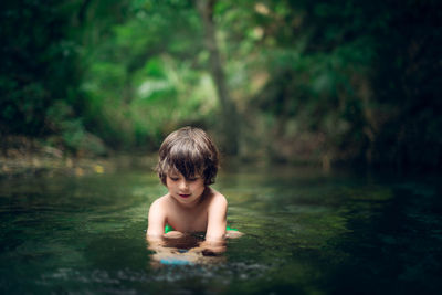 Shirtless cute boy in river at forest