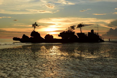 Silhouette trees by sea against sky during sunset