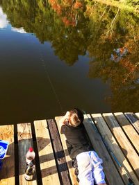 High angle view of man sitting on pier at lake