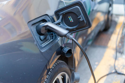 A cable is recharging an electric car at the charging station