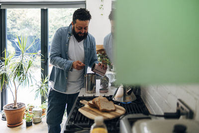 Man preparing coffee while standing at kitchen counter