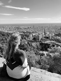 Rear view of woman sitting against buildings in city