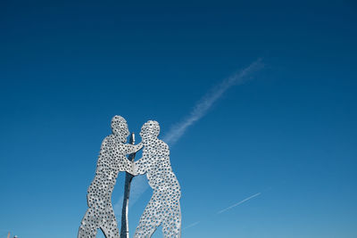 Low angle view of vapor trails against blue sky