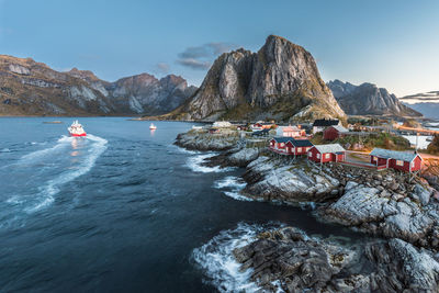 People on sea by mountain against sky