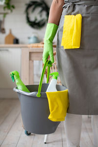 Midsection of woman holding yellow while standing by potted plant