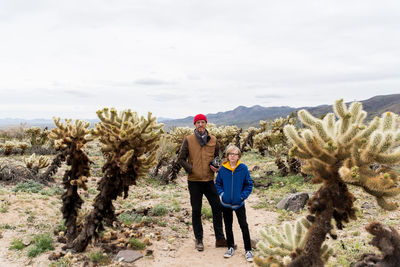 Father and son in cholla cactus field stretching to far off hills