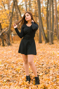 Young woman standing in forest during autumn