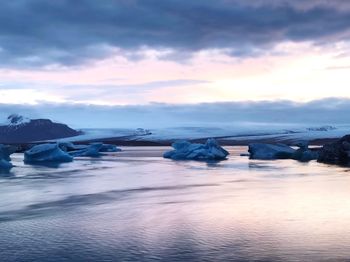 Icebergs in sea against sky during sunset