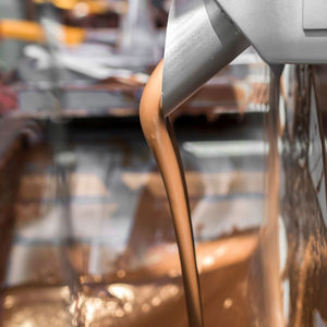 Melted chocolate pouring from machine at factory