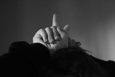 Cropped hand of child pointing over gray background