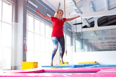 Full length of young woman jumping against window