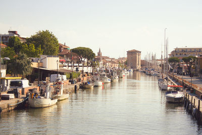 Boats moored in river against buildings in city