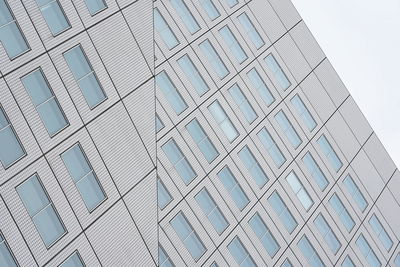 Low angle view of modern glass building in city against sky