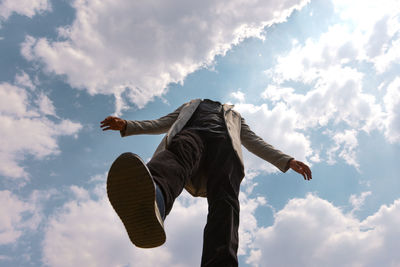 Low angle view of woman jumping against sky