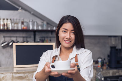 Portrait of a smiling young woman holding camera