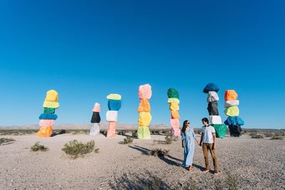 People standing on beach against clear blue sky