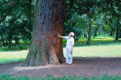 Man standing by tree trunk in park