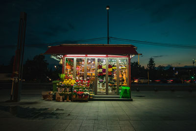 Illuminated street market against sky at night