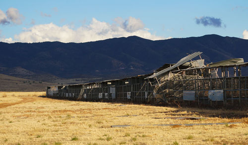 Built structure on field by mountains against sky