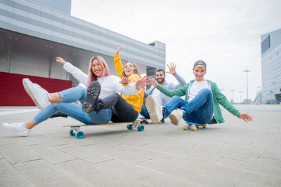 Cheerful friends sitting on skateboard