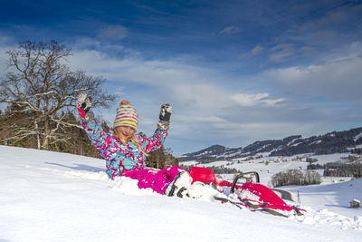 Girl on snow covered field against sky