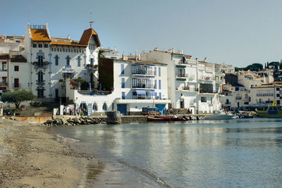 Buildings by sea against clear sky