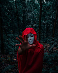 Portrait of man wearing mask while standing by trees in forest