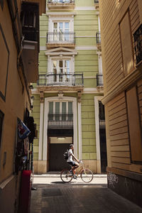 Man riding bicycle on street amidst buildings in city