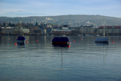 Boats moored at harbor against sky